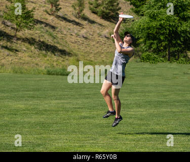Un giovane molto montare donna salta in aria, e concentrati come ella si ritiene che le catture di un flying disc Foto Stock