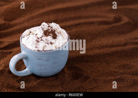 Primo piano dei gustosi caffè e panna montata. Cup su un tavolo ricoperto con caffè macinato Foto Stock