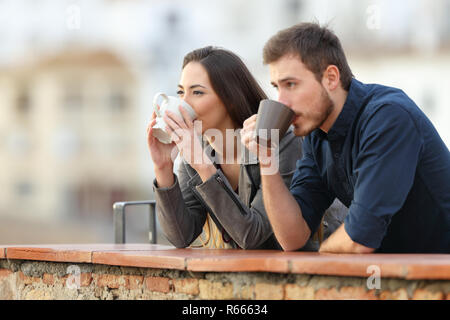 Coppia felice di bere il caffè guardando le visualizzazioni in una terrazza Foto Stock