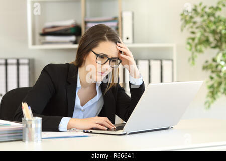 Preoccupato per il lavoratore di ufficio la lettura di cattive notizie online in un computer portatile Foto Stock