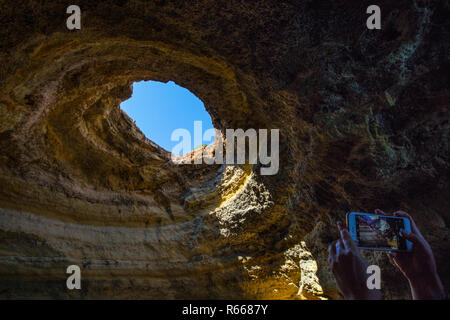 Il ALGRAVE, Portogallo - 16 Luglio 2018: un turista prende le foto sul suo telefono interno la splendida a Benagil grotte situate nella regione dell'Algarve del Portogallo Foto Stock