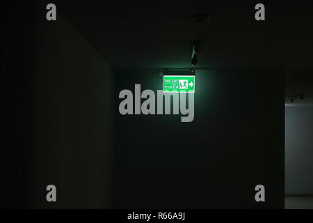 Illuminazione dal fire exit segno nel corridoio scuro di un edificio Foto Stock