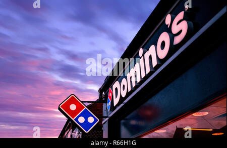 Immagine del tramonto di un negozio di fronte illuminata dei Dominos pizza segno a Rotherham, South Yorkshire, Inghilterra Foto Stock