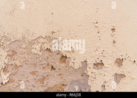 Vista ravvicinata di un vecchio muro con rustici snocciolate e peeling crema-vernice colorata, gesso e stucco Foto Stock