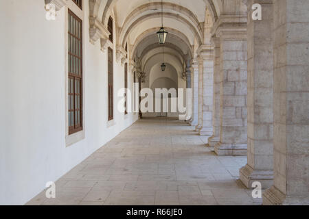 Passaggio lungo lo spostamento di prospettiva sotto arcate con colonne su un lato e un muro bianco sull'altro lato di Lisbona, Portogallo Foto Stock