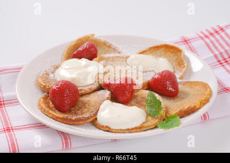 Piccoli pancake con crema e fragole Foto Stock