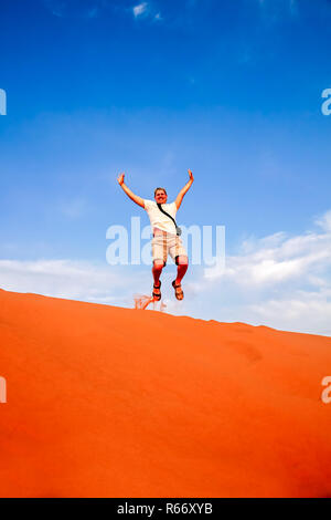 Tourist jumping over the sand dunes in Merzouga Foto Stock