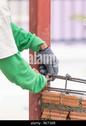 Lavoratori con filo di acciaio e di pinze rebar prima del getto in calcestruzzo Foto Stock