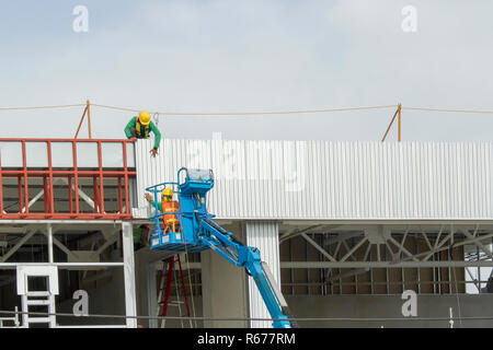 I lavoratori in cestelli sono l'installazione di lamiera, la costruzione di una fabbrica. Foto Stock