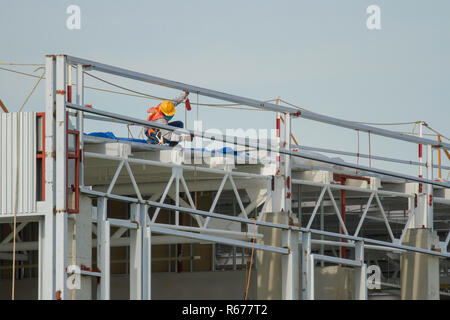 I lavoratori in cestelli sono l'installazione di lamiera, la costruzione di una fabbrica. Foto Stock