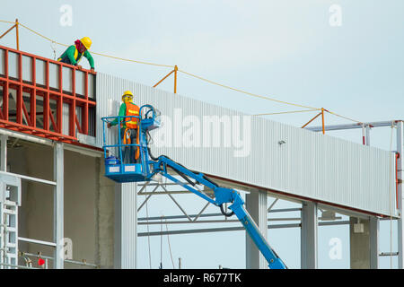 I lavoratori in cestelli sono l'installazione di lamiera, la costruzione di una fabbrica. Foto Stock