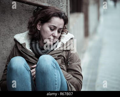 Donna attraente affetti da depressione abbattimento triste infelice heartbroken e solitaria seduta in città strada urbana in salute mentale dolore emotivo Abu Foto Stock