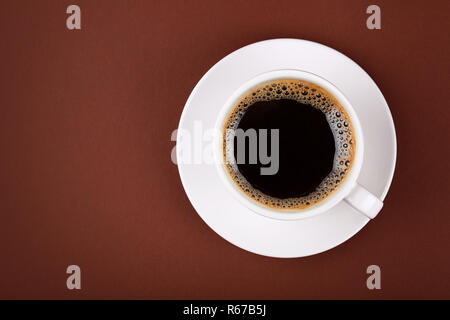 Tazza piena di caffè nero in tazza bianco su marrone Foto Stock
