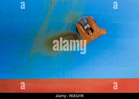 Il dispositivo di ancoraggio è arrugginito con il blu e il rosso sfondi e vecchio. Foto Stock