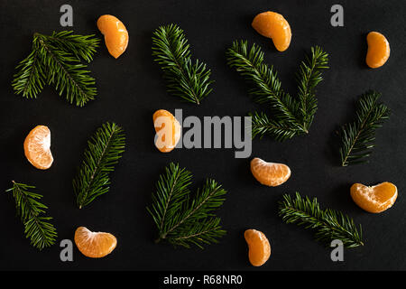 Piatto modello di laici di arancio mandarino fette e piccoli rami d abete sulla trama scuro dello sfondo. Foto Stock