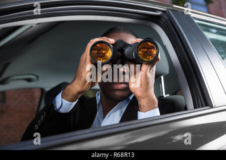 L'uomo africano guardando attraverso il binocolo Foto Stock