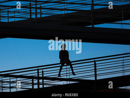 Ragazzo seduto sul ponte che attraversa la strada statale, contemplando l'orizzonte al tramonto, Provincia di Huila, Lubango, Angola Foto Stock