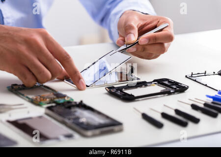 Il tecnico di fissaggio schermo danneggiato sul telefono cellulare Foto Stock