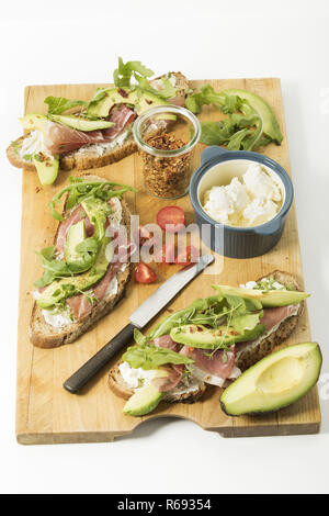 Cipolla rustico pane con formaggio fresco prosciutto di Parma Avocado Rucola Timo peperoncino e pomodoro Foto Stock