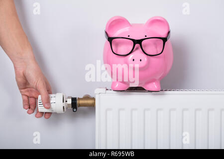 Man mano del termostato di regolazione con il salvadanaio Foto Stock