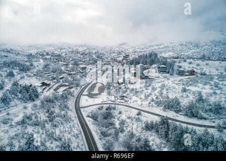 Vista aerea di Seli tradizionale villaggio Greco coperta di neve. Montagne e strada durante d'inverno. Top destinazione turistica in Grecia settentrionale Foto Stock