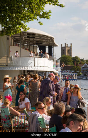 I membri e i loro ospiti in steward' involucro a Henley Royal Regatta con la Chiesa di Santa Maria, Henley-on-Thames in background Foto Stock