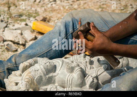 Una stone mason scalpelli i tocchi di rifinitura per i suoi religiosi indù stone carving. Foto Stock