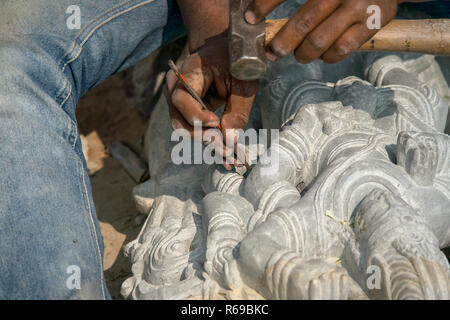 Una stone mason scalpelli i tocchi di rifinitura per i suoi religiosi indù stone carving. Foto Stock