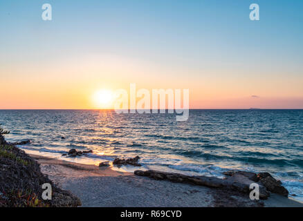 Panorama di un tramonto sul mar Mediterraneo su un'isola greca. Foto Stock