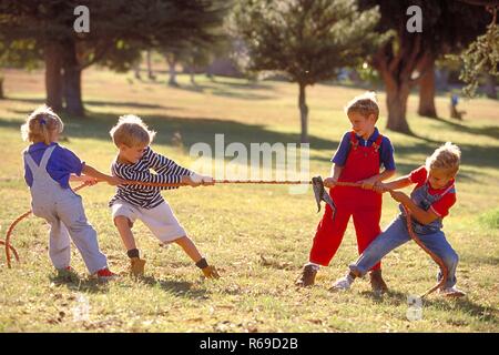 All'aperto, Parkszene, Gruppe von vier Kindern, 5-8 Jahre, spielen Tau Ziehen auf einer Wiese Foto Stock