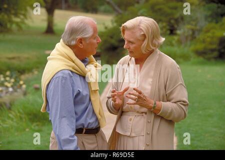All'aperto, Ritratto, Halbfigur, weisshaariges Seniorenpaar bekleidet mit heller Kleidung unterhaelt sich in einem Park Foto Stock