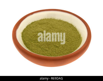 Vista laterale di una porzione di organico la polvere di erba di frumento in un piccolo recipiente isolato su uno sfondo bianco. Foto Stock