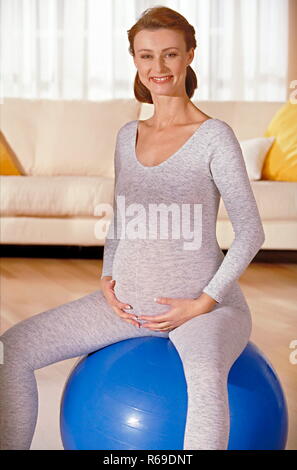 Ritratto, schwangere Frau sitzt auf einem blauen Gymnastikball Foto Stock