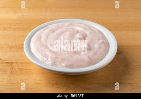 Una tazza di fragole e rabarbaro yogurt dolcificate con miele su una tavola di legno. Foto Stock