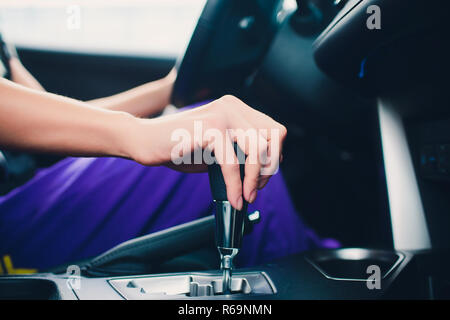 Vicino la giovane donna mano sul cambio automatico della marcia, il cambio di marcia cambio in auto.Driver donna mano azienda trasmissione automatica o di azionamento a velocità variabile in auto, cambio marcia stick prima di guidare la macchina. Foto Stock