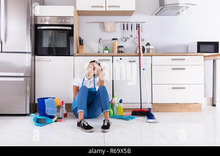 Giovane donna seduta sul pavimento della cucina Foto Stock