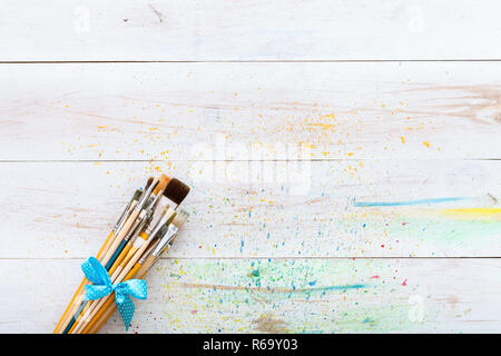 Pennelli per dipingere impostato su Bianco verniciato in legno colorato tavolo con schizzi, tela artistica sfondo, spazio creativo per la verniciatura, pittore workplace, chi Foto Stock