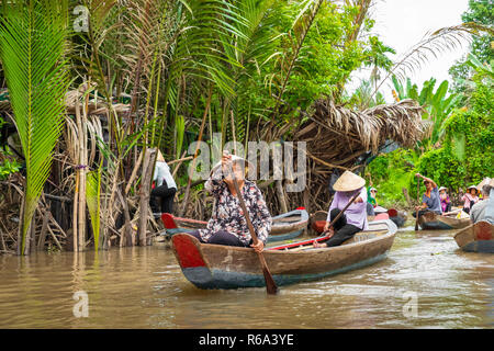 MY THO, VIETNAM - Novembre 24, 2018: Fiume Mekong Delta crociera nella giungla con artigiani non identificato e fisherman barche a remi per le inondazioni fangoso lotus fi Foto Stock