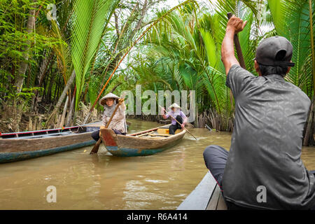 MY THO, VIETNAM - Novembre 24, 2018: Fiume Mekong Delta crociera nella giungla con artigiani non identificato e fisherman barche a remi per le inondazioni fangoso lotus fi Foto Stock