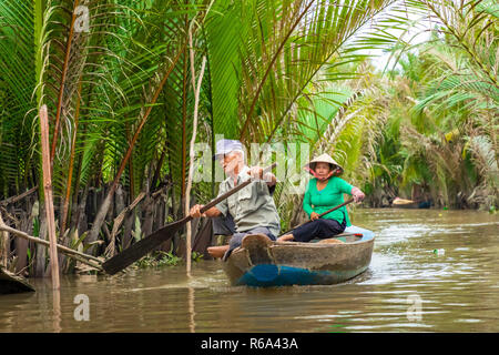 MY THO, VIETNAM - Novembre 24, 2018: Fiume Mekong Delta crociera nella giungla con artigiani non identificato e fisherman barche a remi per le inondazioni fangoso lotus fi Foto Stock