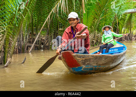 MY THO, VIETNAM - Novembre 24, 2018: Fiume Mekong Delta crociera nella giungla con artigiani non identificato e fisherman barche a remi per le inondazioni fangoso lotus fi Foto Stock