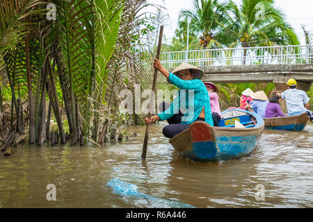 MY THO, VIETNAM - Novembre 24, 2018: Fiume Mekong Delta crociera nella giungla con artigiani non identificato e fisherman barche a remi per le inondazioni fangoso lotus fi Foto Stock