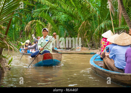 MY THO, VIETNAM - Novembre 24, 2018: Fiume Mekong Delta crociera nella giungla con artigiani non identificato e fisherman barche a remi per le inondazioni fangoso lotus fi Foto Stock