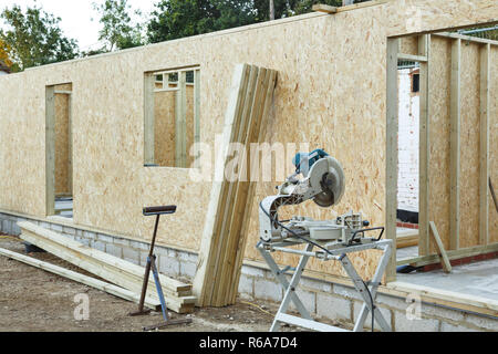 Una casa con struttura in legno è costruito utilizzando OSB i fogli per formare pannelli di legno. Carpenter's chop vide in primo piano Foto Stock