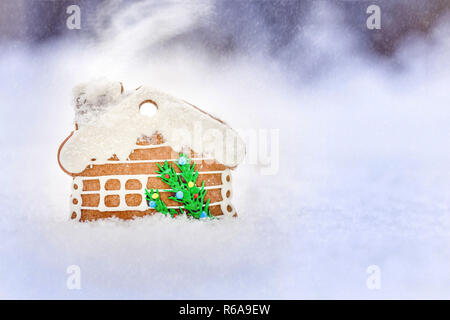 Gingerbread house su una neve sullo sfondo all'aperto, scheda di Natale , neve e effetto fumo, iscrizione di Buon Natale e felice anno nuovo Foto Stock