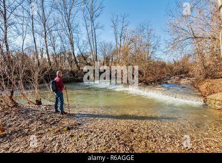 Escursionista di circa 60 anni, sulla riva del torrente. Foto Stock