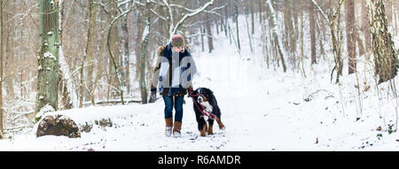 Donna con il suo cane escursioni o passeggiate in inverno Foto Stock