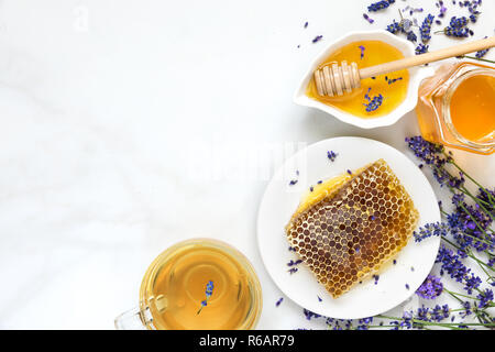 Miele di lavanda con tè e favi con fiori freash su marmo bianco tavola. Il cibo sano. vista superiore con spazio di copia Foto Stock