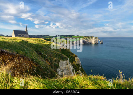 Etretat, Normandia, Francia. Scogliere, la chiesa e la bellissima famoso litorale durante la marea di sunrise Foto Stock