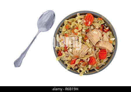 Vista dall'alto di una casa fatta una zuppa di noodle al pollo in un vecchio recipiente di ceramica con un cucchiaio a lato isolato su uno sfondo bianco. Foto Stock